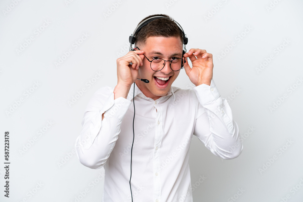 Telemarketer Brazilian man working with a headset isolated on white background with glasses and surprised Telemarketer Brazilian man working with a headset isolated on white background with glasses and surprised