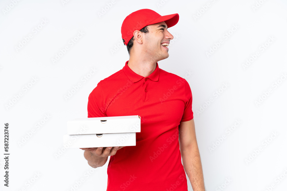 Pizza delivery caucasian man with work uniform picking up pizza boxes isolated on white background laughing in lateral position Pizza delivery caucasian man with work uniform picking up pizza boxes isolated on white background laughing in lateral position