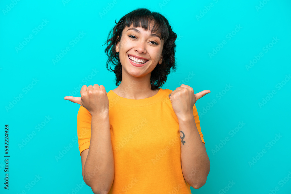 Young Argentinian woman isolated on blue background with thumbs up gesture and smiling Young Argentinian woman isolated on blue background with thumbs up gesture and smiling