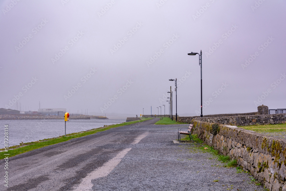 Foggy road in the morning by coast line with street lamps lined up