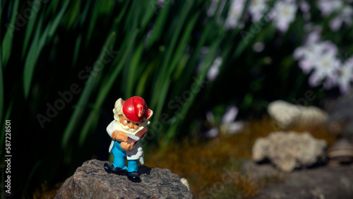 Gnome figurine in the garden.Flower bed with fairy-tale characters.Bright locations with fabulous characters.