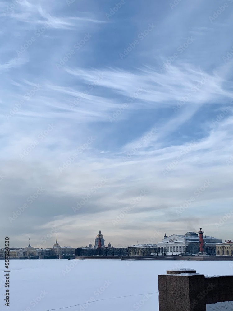 View from Mytninskaya embankment to the ice-covered Neva, Spit of Vasilevsky Island, Rostral columns and St. Isaac's Cathedral. Against the background of the sky with beautiful clouds in St. Petersbur