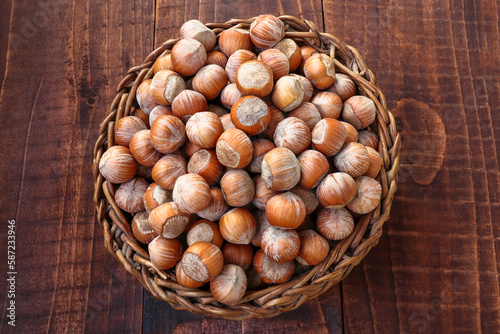 Old basket of hazelnuts, wooden background. Top view