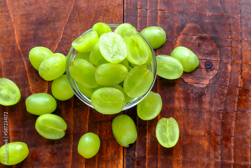 Green grapes in a glass bowl on a wooden background