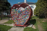 Pojemnik w kształcie serca do zbierania plastikowych nakrętek, ustawiony w miejscu publicznym