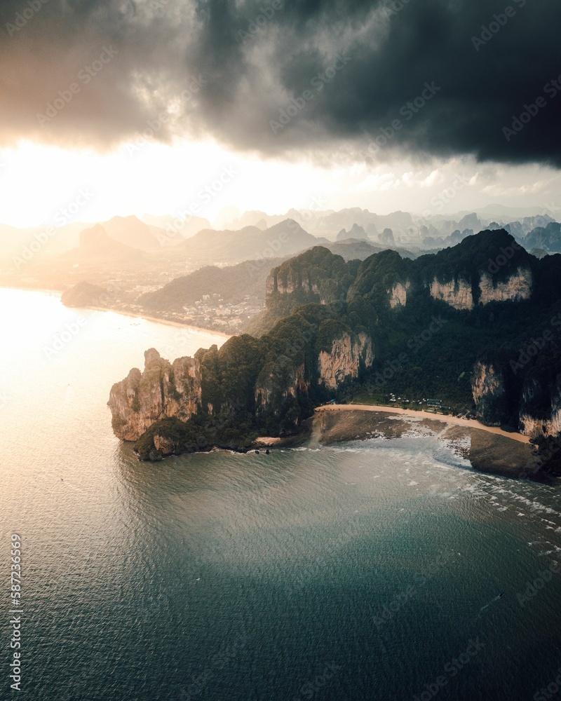 Aerial view of a forested green rocky island with a sandy beach in Thailand, Krabi, Railay Bay
