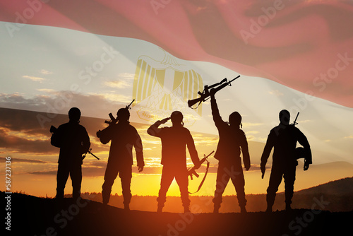 Double exposure of silhouettes of a soliders and the sunset or the sunrise against flag of Egypt.