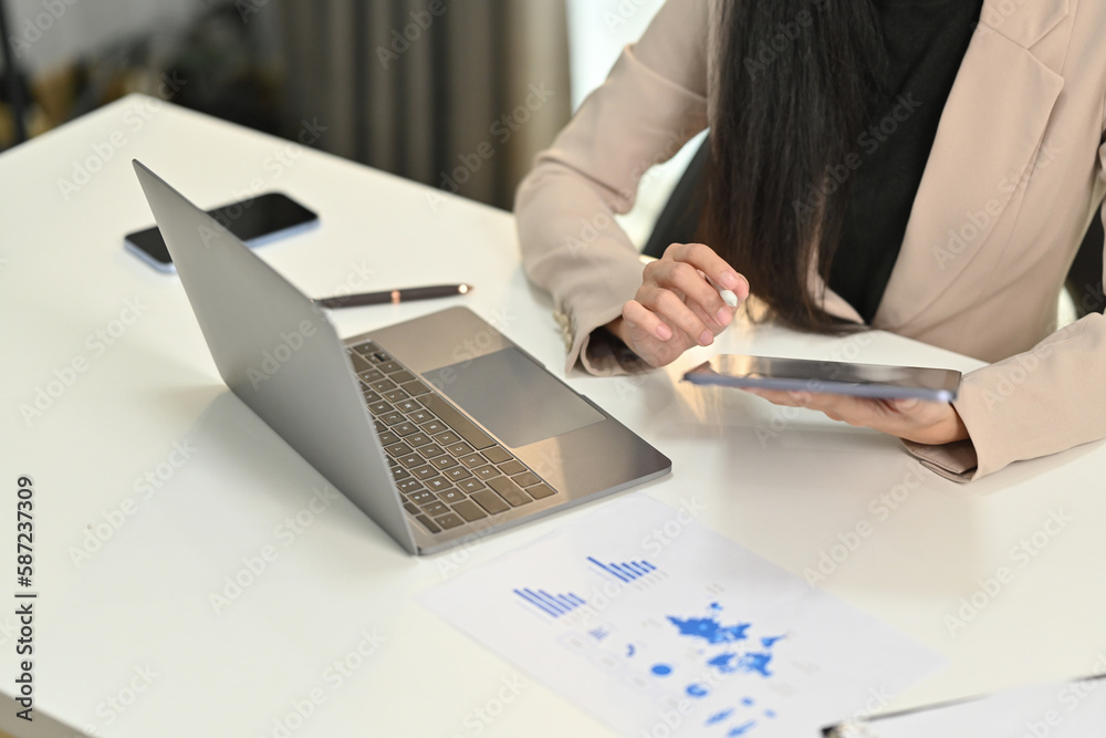 Female accountant using digital tablet and working on bookkeeping documents, checking financial data at office Female accountant using digital tablet and working on bookkeeping documents, checking financial data at office