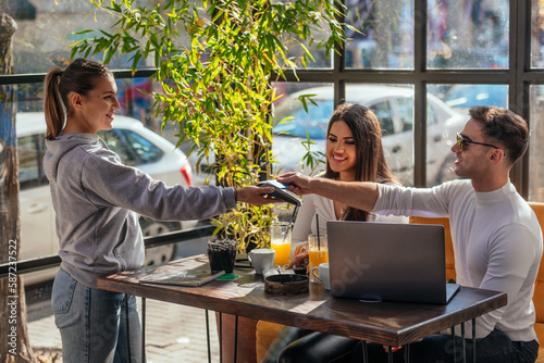 Side view of a couple paying bill at coffee shop using credit card payment