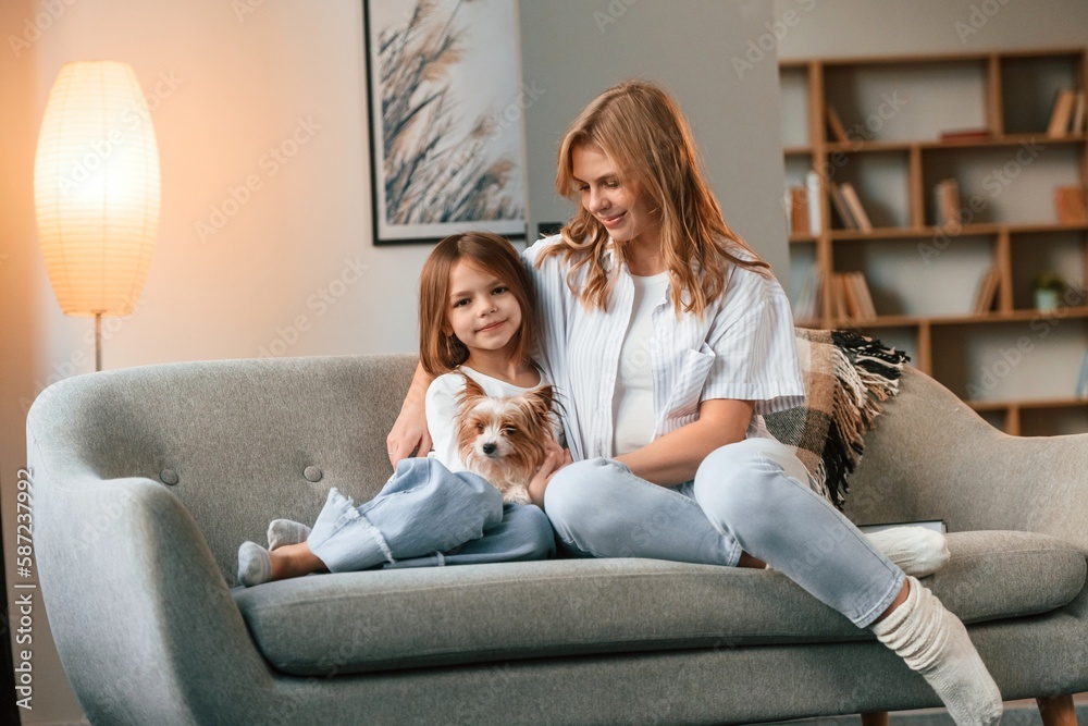Beautiful animal. Mother with her daughter and with cute dog is in domestic room
