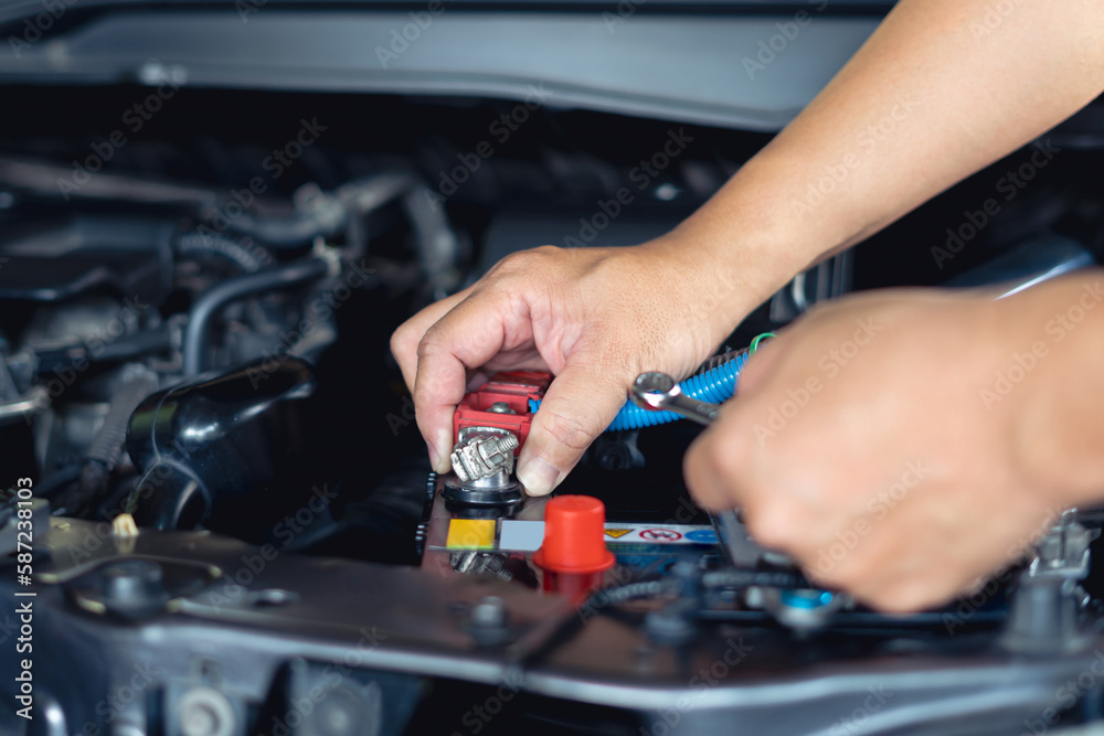 Car service concept and battery replacement, A man use wrench unlock bolt of Battery terminal change new car battery in engine room , service concept and car mainternance Car service concept and battery replacement, A man use wrench unlock bolt of Battery terminal change new car battery in engine room , service concept and car mainternance