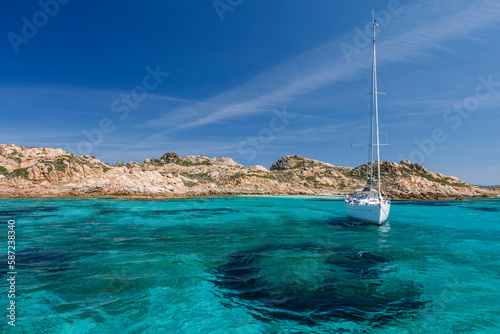 foto panoramica di una costa con il mare cristallino e una barca a vela photo