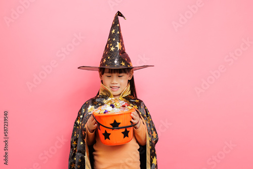 Happy Halloween! young girl with  witch costume and hold a candy bucket against plain  background © M-image