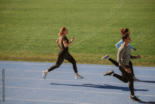 Three friends running on a blue sports track
