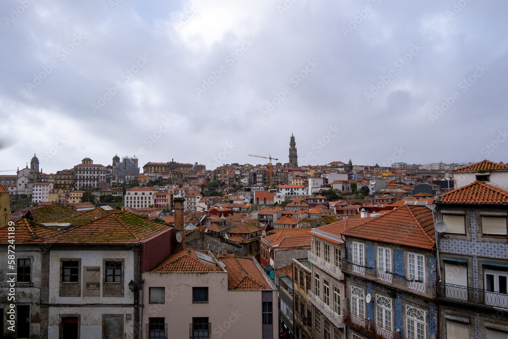 Panorámica de la ciudad de Oporto con los tejados rojos y las fachadas de colores bajo un cielo nublado.