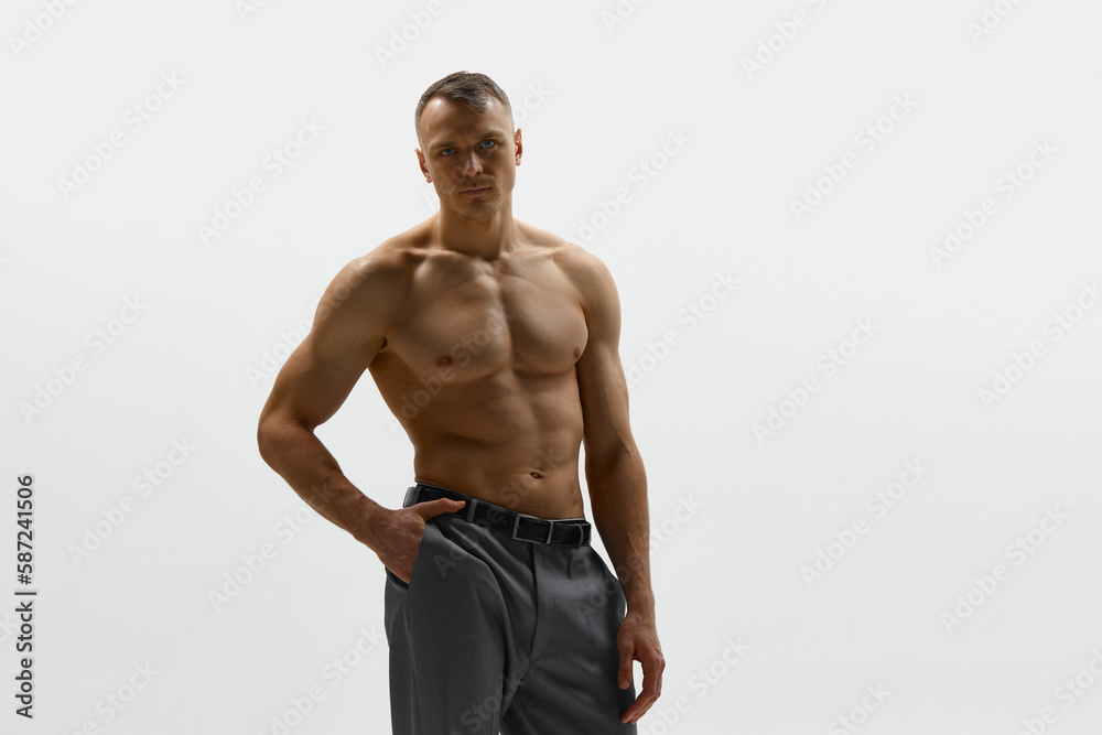 Fototapeta premium Sexy portrait of muscular handsome topless male model posing at camera over white studio background