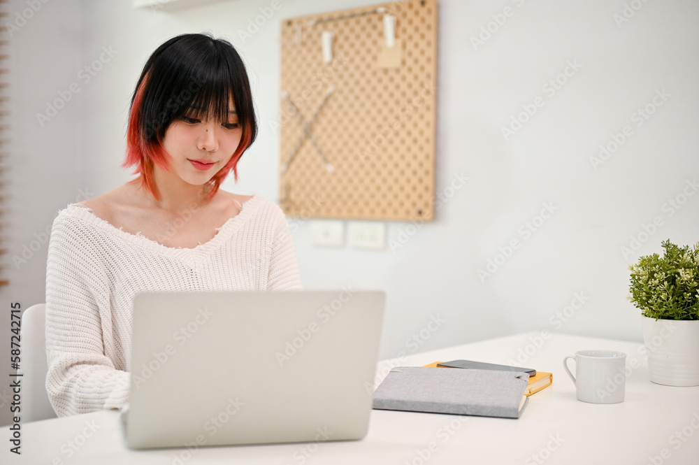 Focused Asian woman browsing internet, reading online articles, or working on her tasks Focused Asian woman browsing internet, reading online articles, or working on her tasks