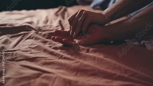 Closeup of couple hands caressing on bed