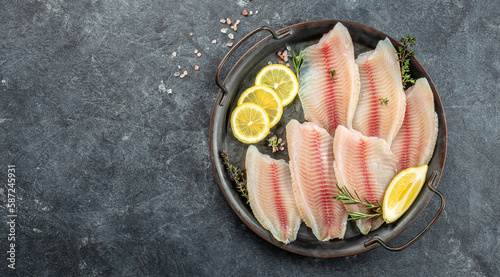 Foto Raw tilapia fish fillet sliced for steak with lemon and spices on a dark background