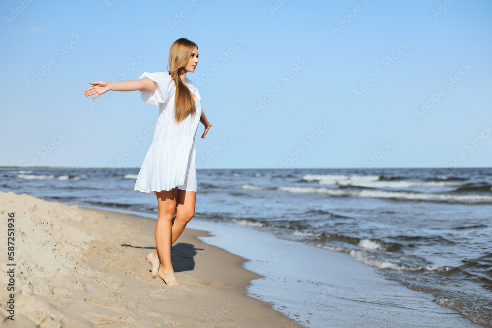 Happy smiling beautiful woman is walking on the ocean beach with open arms Happy smiling beautiful woman is walking on the ocean beach with open arms