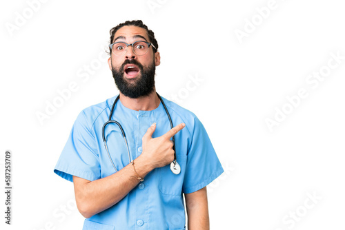 Young doctor man over isolated chroma key background surprised and pointing side