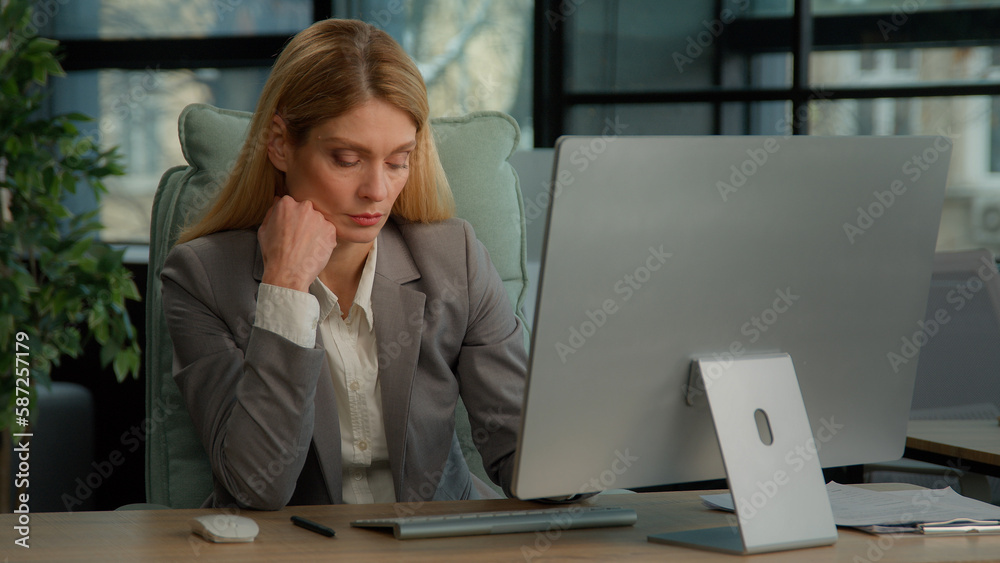 Serious tired exhausted businesswoman Caucasian middle-aged adult woman focused female executive manager sitting at desk working typing computer overworked with business project in corporation office Serious tired exhausted businesswoman Caucasian middle-aged adult woman focused female executive manager sitting at desk working typing computer overworked with business project in corporation office