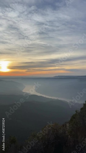 sunset from the top of a mountain, with a warm light and clear sky, illuminating the water of the river on a summer afternoon