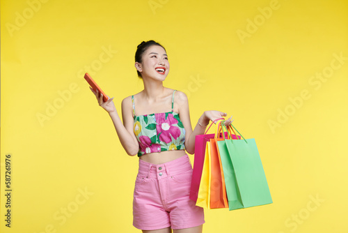 Beautiful Attractive Asian Woman holding shopping bags and mobile phone over bachground