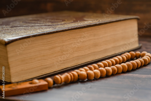 Islamic holy book Quran on wooden table background with tasbih . Ramadan kareem / Eid Mubarak Concept