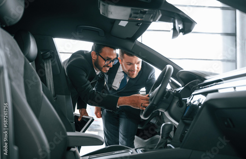 Man showing automobile interior to the customer