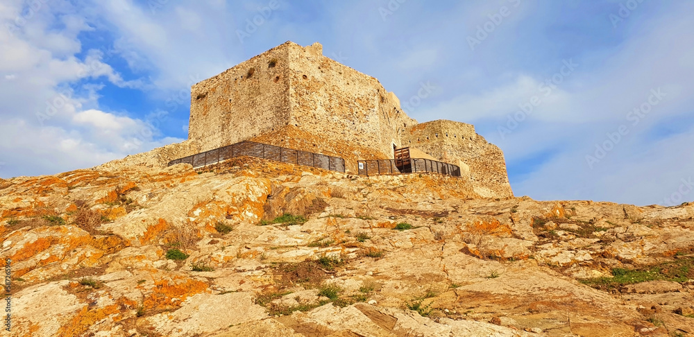 The stone castle of Volterraio stands on a mountain against the blue sky. Panorama.