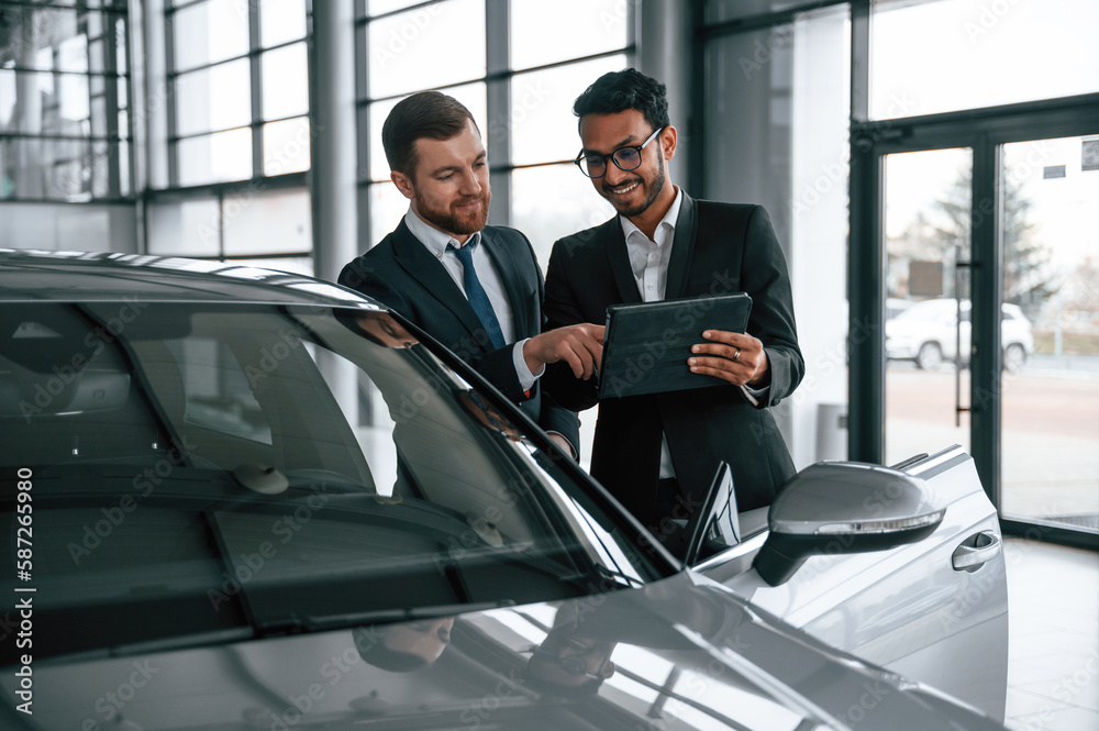 Man is consulting the customer in the car showroom Man is consulting the customer in the car showroom
