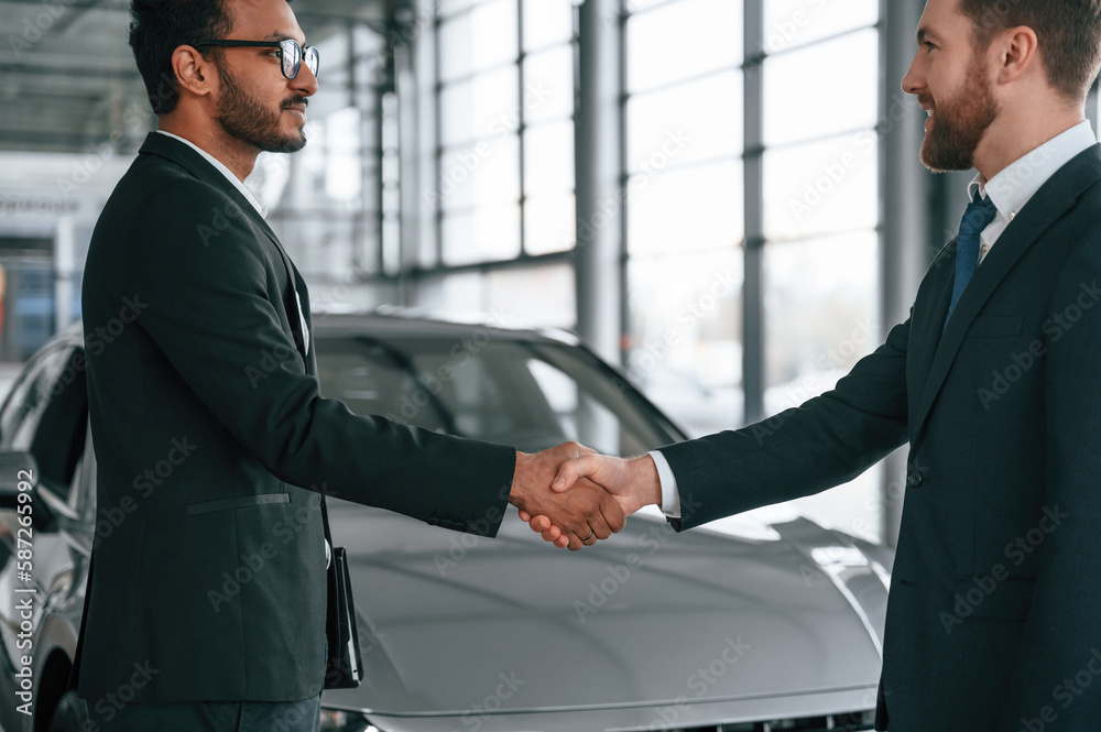 Two businessmen are working together in the car showroom Two businessmen are working together in the car showroom