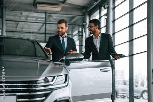 Standing and talking near automobile. Man is consulting the customer in the car showroom © standret