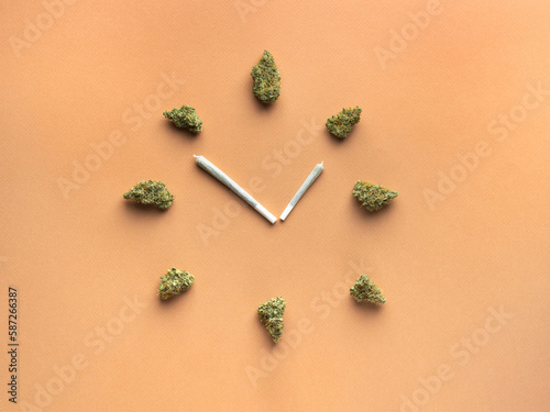 Joints with cannabis in the form of clock hands, dry marijuana buds represent the numbers of the clock.  The arrows indicate the time 4:20 pm.  On a light brown background