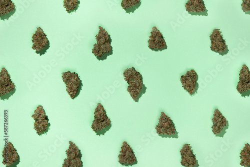 A pattern of dry buds of medical marijuana arranged in a checkerboard pattern, on a mint background.