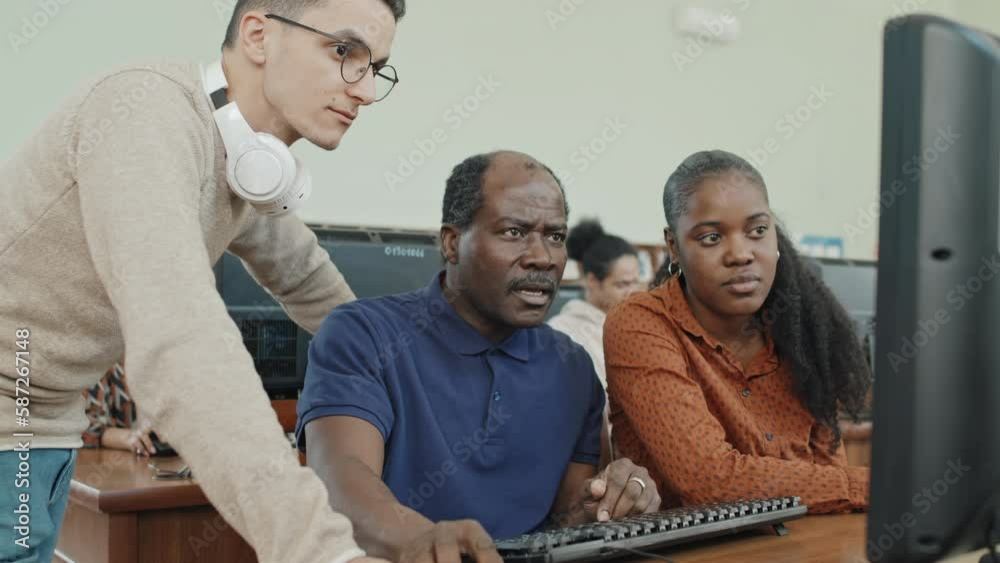 Group of ethnically diverse migrant students working on project together using desktop computer in library