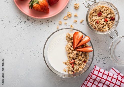 Strawberry organic granola with milk and fresh berries on light kitchen board.