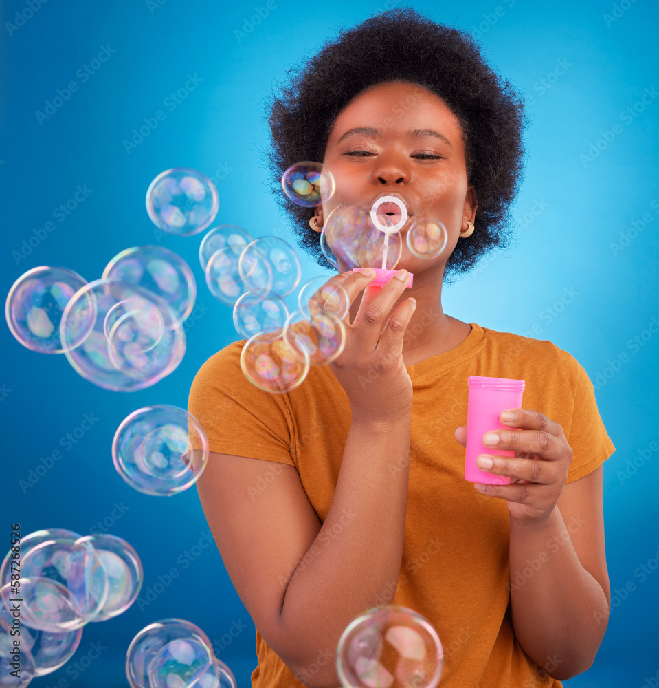 Fun, bubbles and black woman with joy, positive attitude and happiness against a blue studio background. African American female, lady and soap bubble for joy, playing and cheerful with excitement Fun, bubbles and black woman with joy, positive attitude and happiness against a blue studio background. African American female, lady and soap bubble for joy, playing and cheerful with excitement