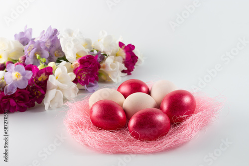 pink nest with bright pink easter eggs and colorful spring flowers on a white background. easter decor. selective focus