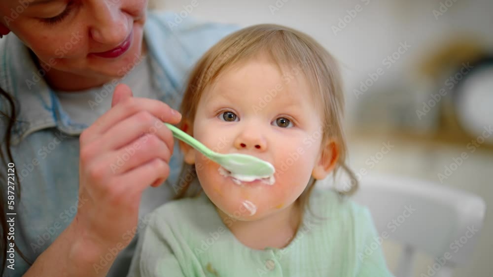 mom-trying-to-feed-toddler-baby-vegetable-puree-from-plastic-spoon