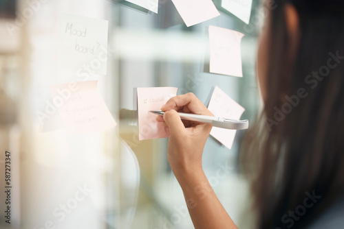 Hands, brainstorming and woman writing notes for office schedule, agenda and mindmap goals at window. Closeup female employee planning ideas at glass for solution, information and strategy objectives photo