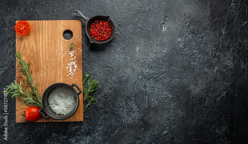 cooking background with wooden cutting board with spices, tomatoes and herbs. Long banner format. top view