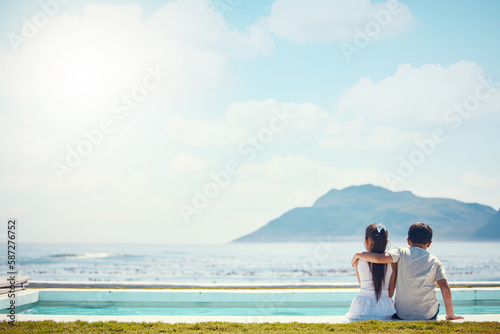 Siblings, hug and love with back by beach, sea and horizon in mock up space for friends, holiday or outdoor. Kids, girl and boy with support by mountain, ocean or waves for mockup in summer vacation