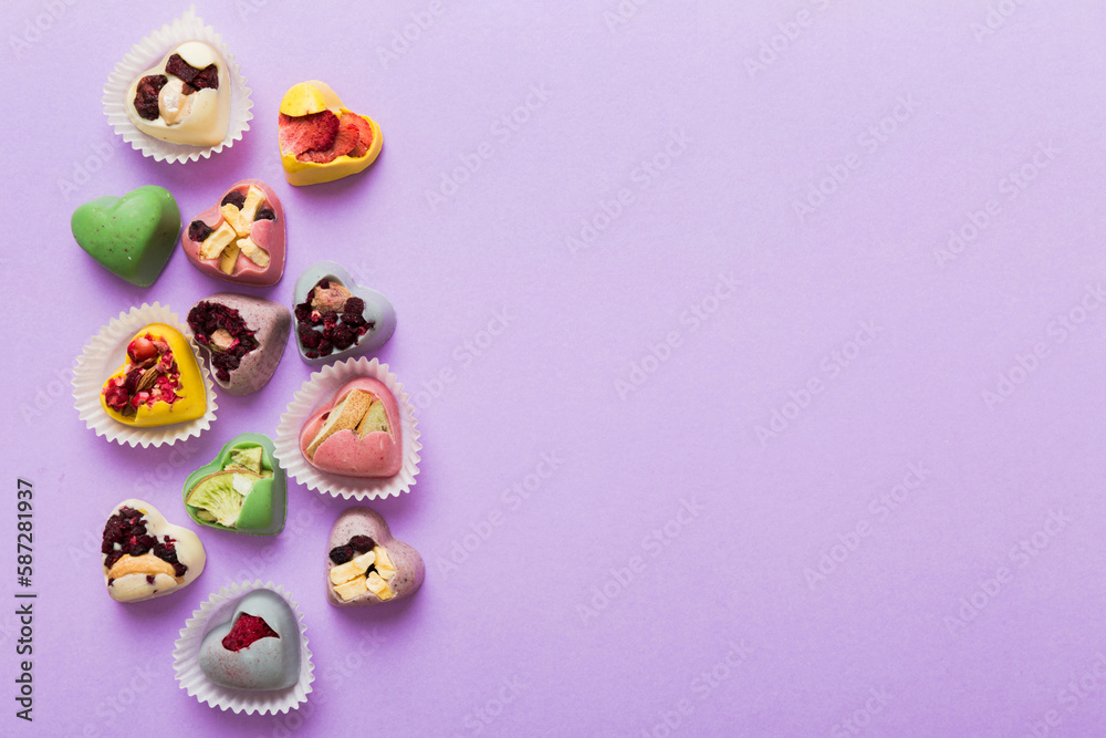 chocolate sweets in the form of a heart with fruits and nuts on a colored background. top view with space for text, holiday concept chocolate sweets in the form of a heart with fruits and nuts on a colored background. top view with space for text, holiday concept