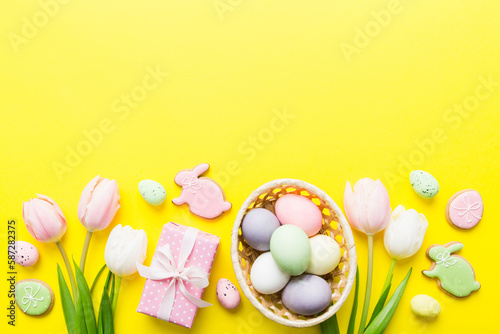 Easter frame with eggs, gift box and tulip on a colored background. The minimal concept. Top view Happy Easter composition. Card with a copy space of the place for the text