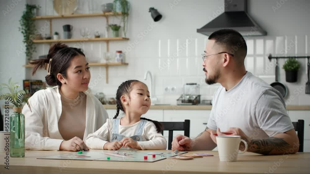 Family Playing Board Game. Happy Asian family with one kid plays board card game with dies sitting at home. Family Playing Board Game. Happy Asian family with one kid plays board card game with dies sitting at home.