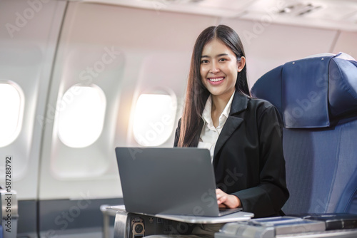 Female passenger sitting on plane while working on laptop computer with simulated space using on board wireless connection