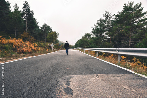 persona paseando por la carretera en la montaña entre arboles