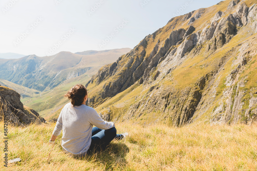 Chica sentada relajada en la montaña observando el paisaje 
